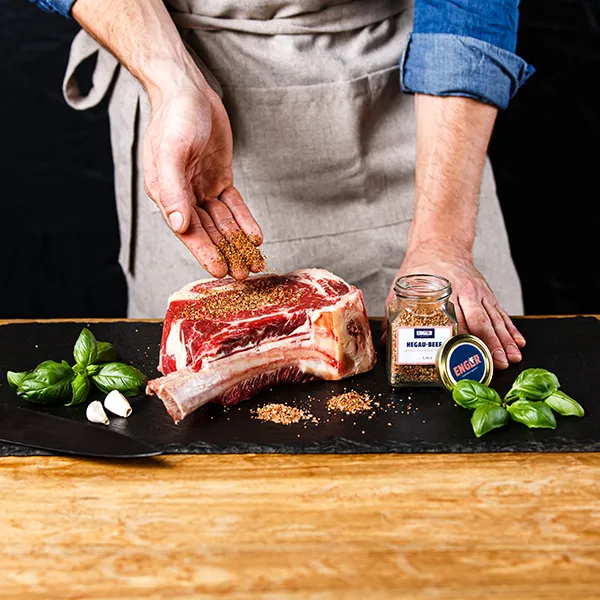 Metzger würzt ein Steak.