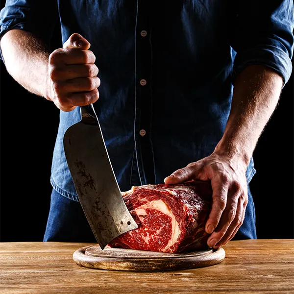 Metzger zerteilt Rohfleisch mit Hackbeil.