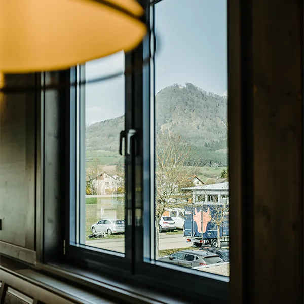 Blick aus dem Fenster auf Hügel, Autos und Firmengebäude.