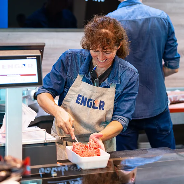 Mitarbeiterin füllt Hackfleisch an der Verkaufstheke ab.