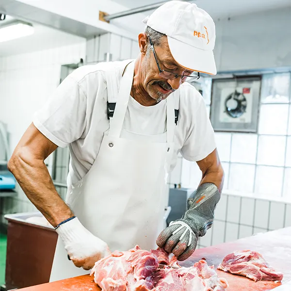 Metzger verarbeitet rohes Fleisch auf dem Schneidetisch.