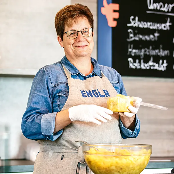 Mitarbeiterin der Metzgerei Engler mit Schürze hält Kartoffesalat Schale.